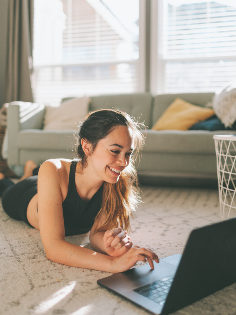 Woman doing a guided seated stretch at home, following an exercise on her laptop